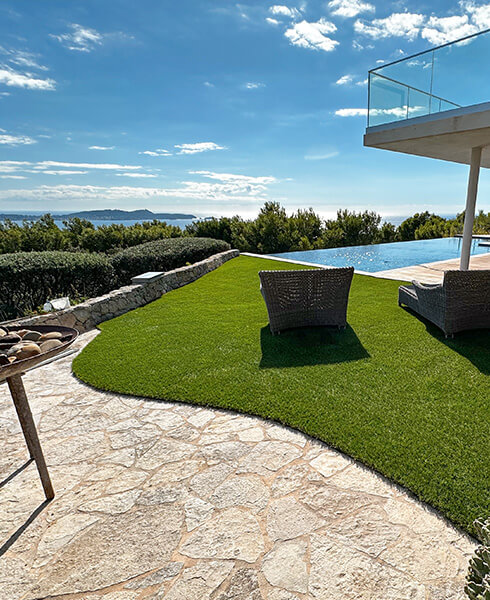 Exemple de pelouse synthétique installée sur un terrasse Découpes de gazon synthétique en arrondi sur une terrasse